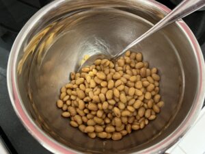 大豆が熱いうちに納豆菌液と混ぜるイメージ